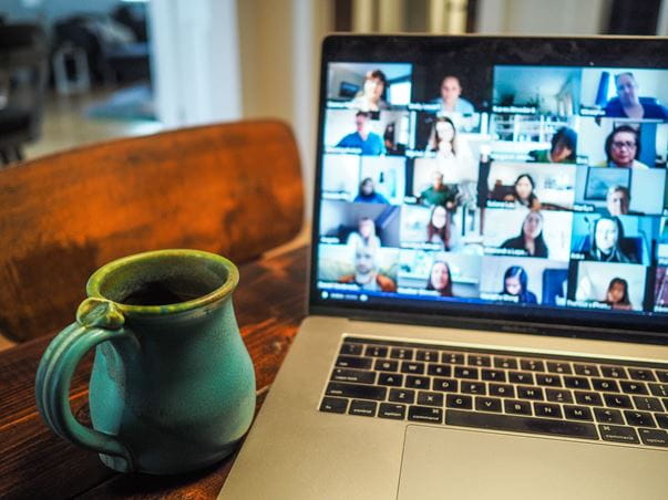 hybrid team meeting on laptop with a coffee mug