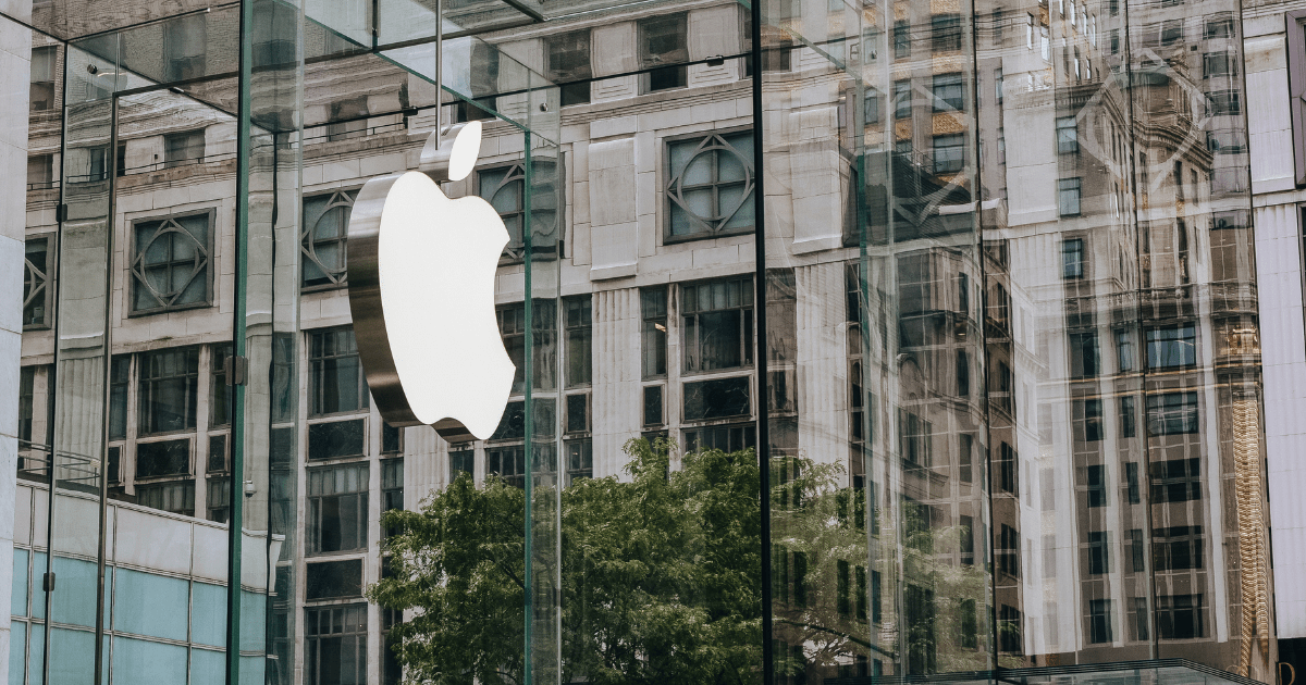 Apple Inc.'s logo on the outside of a mirrored glass building.