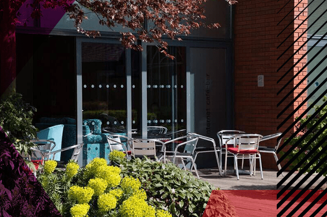 Outdoor communal area at Woodland Grange, with metal tables and chairs and plants for decoration.