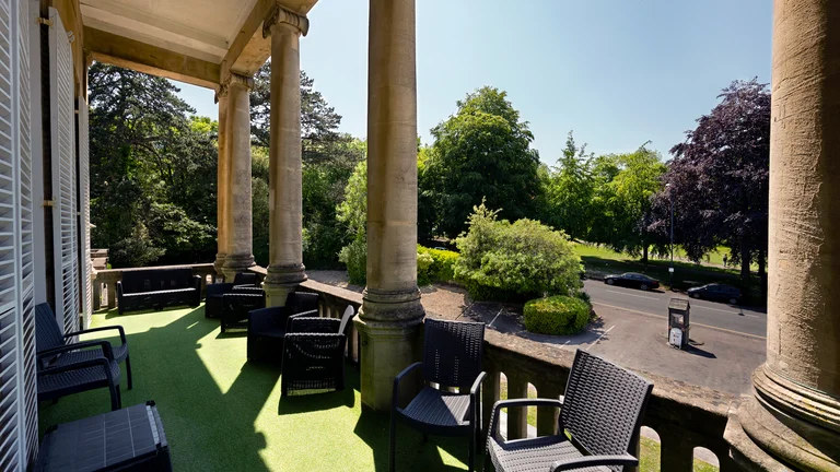 Outside seating area with columns and green space with trees