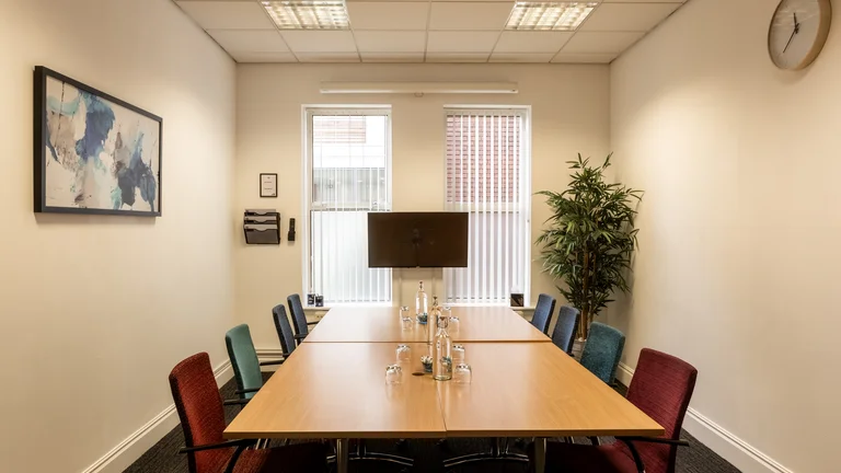 Small meeting room with screen on the wall and pot plant in the corner