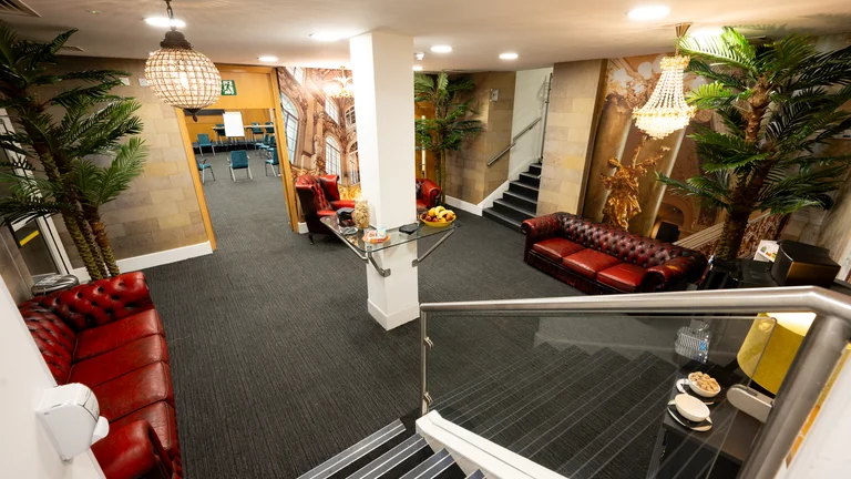 Waiting room in Broadway House with 3 leather couches with baroque print on walls 
