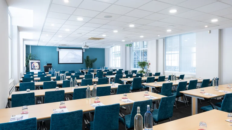 Lecture style meeting room set up with screen on far wall 