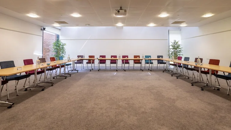 Large meeting room with U-shaped ensemble of chairs and table