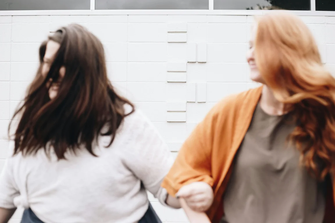 2 women laughing with arms linked 
